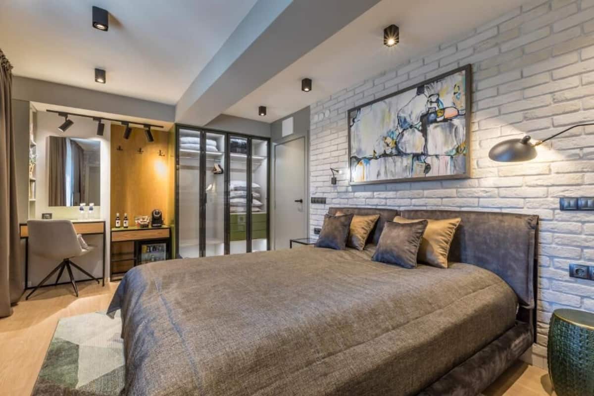 A modern bedroom with a large bed, a desk, and a wardrobe.