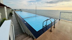 En swimmingpool med utsikt över havet, en trappa och ett räcke.