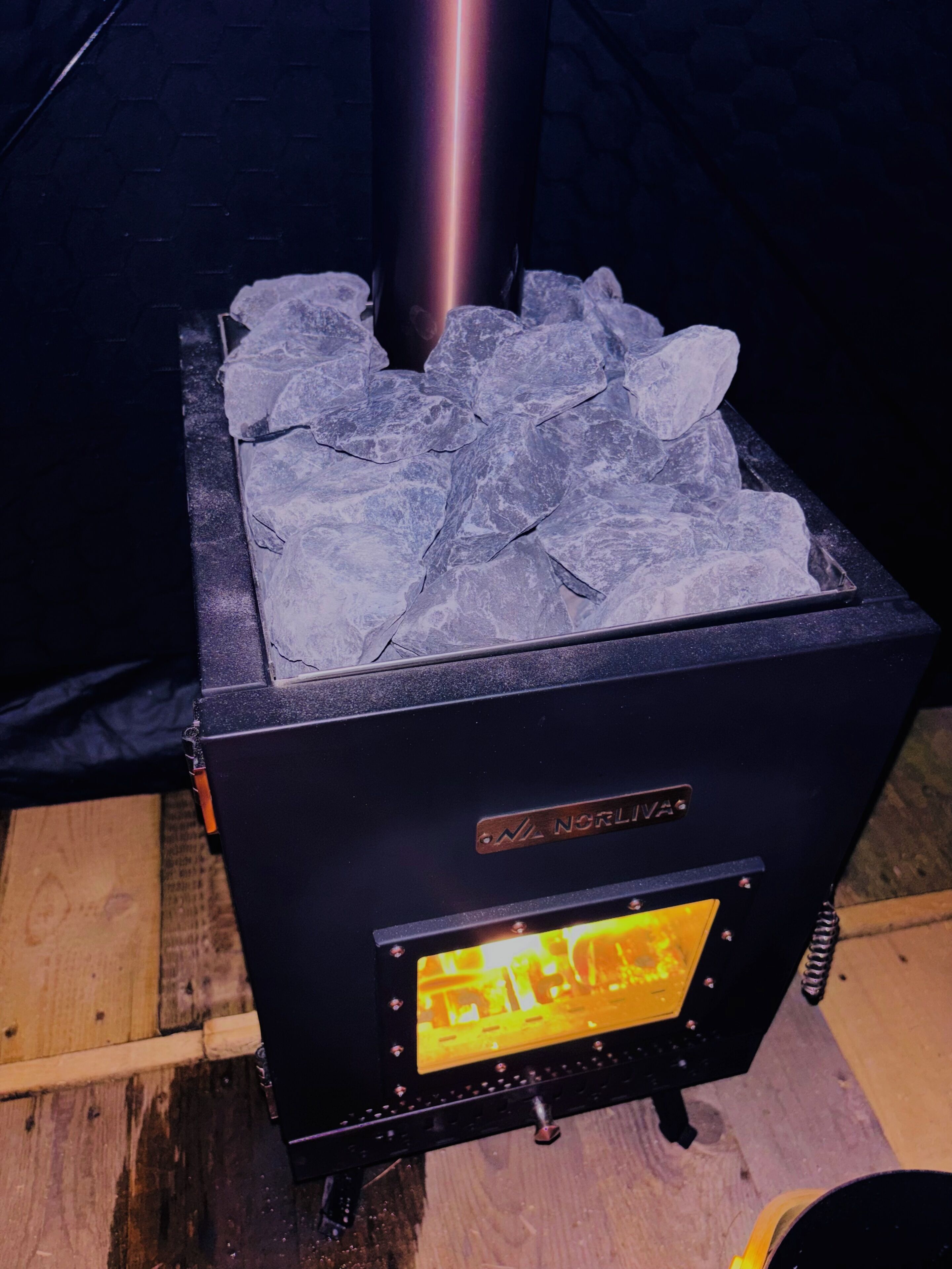 Ein Holzofen mit sichtbarem Markennamen, einer digitalen Anzeige und einem Metallrohr.
