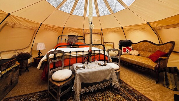A cozy tent interior with a bed, a sofa, and a dining table. - Nordic Experience: Sauna & Cold Bath in the Camargue (Arles)