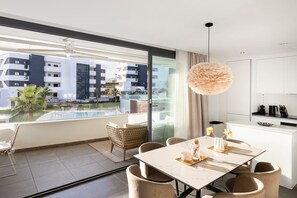 A modern hotel room with a large balcony, a dining area, and a kitchen. - Premium Apartment With Terrace in Higuer n (Fuengirola)
