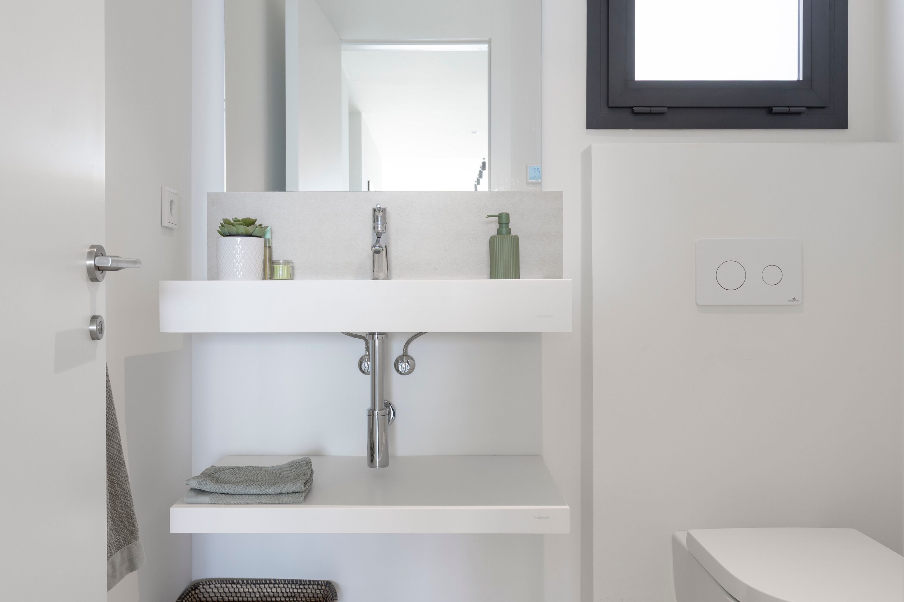 A modern bathroom with a white sink, a mirror, and a toilet.