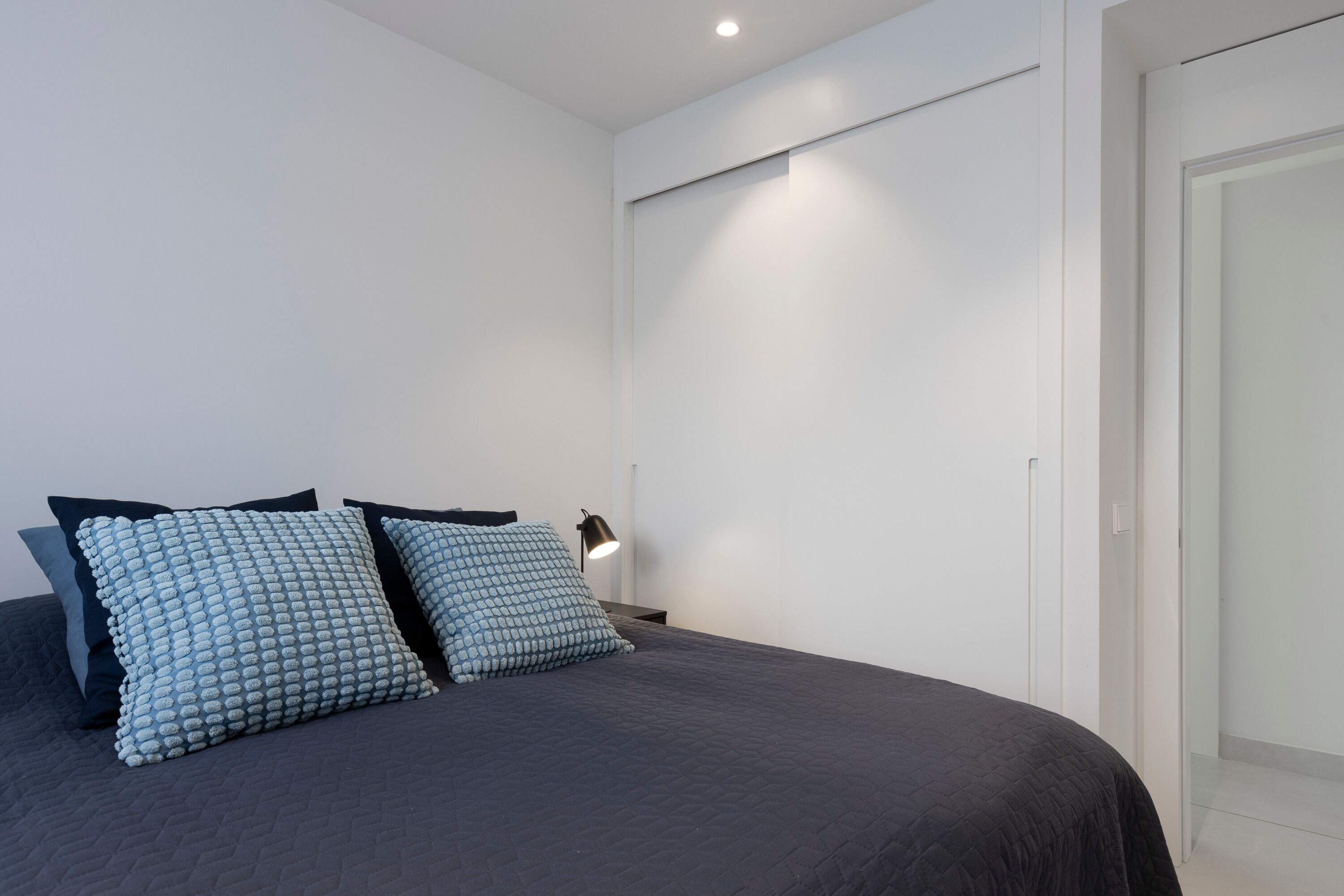 Une chambre moderne avec un grand lit, deux oreillers, une lampe de chevet et une armoire.