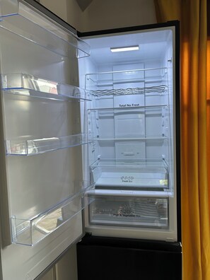 En kylskåpsdörr står öppen och visar uppfack med tydliga etiketter för ”Total No Frost” (frostfri funktion), ”Fresh Box” (fack för färska varor) och ”Fruit & Vegetables Box” (fack för frukt och grönsaker).