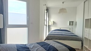 Ein Schlafzimmer mit zwei Betten, einem Fenster, einer Deckenleuchte und einem Kleiderschrank.