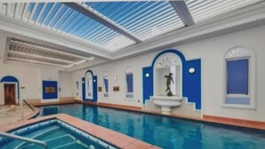 An indoor swimming pool with clear blue water, a diving platform, and a statue of a swimmer. - PHOENICIAN RESORT- Renovated 2 Bed + 2 Bath Unit in the Heart of Broadbeach (Broadbeach)