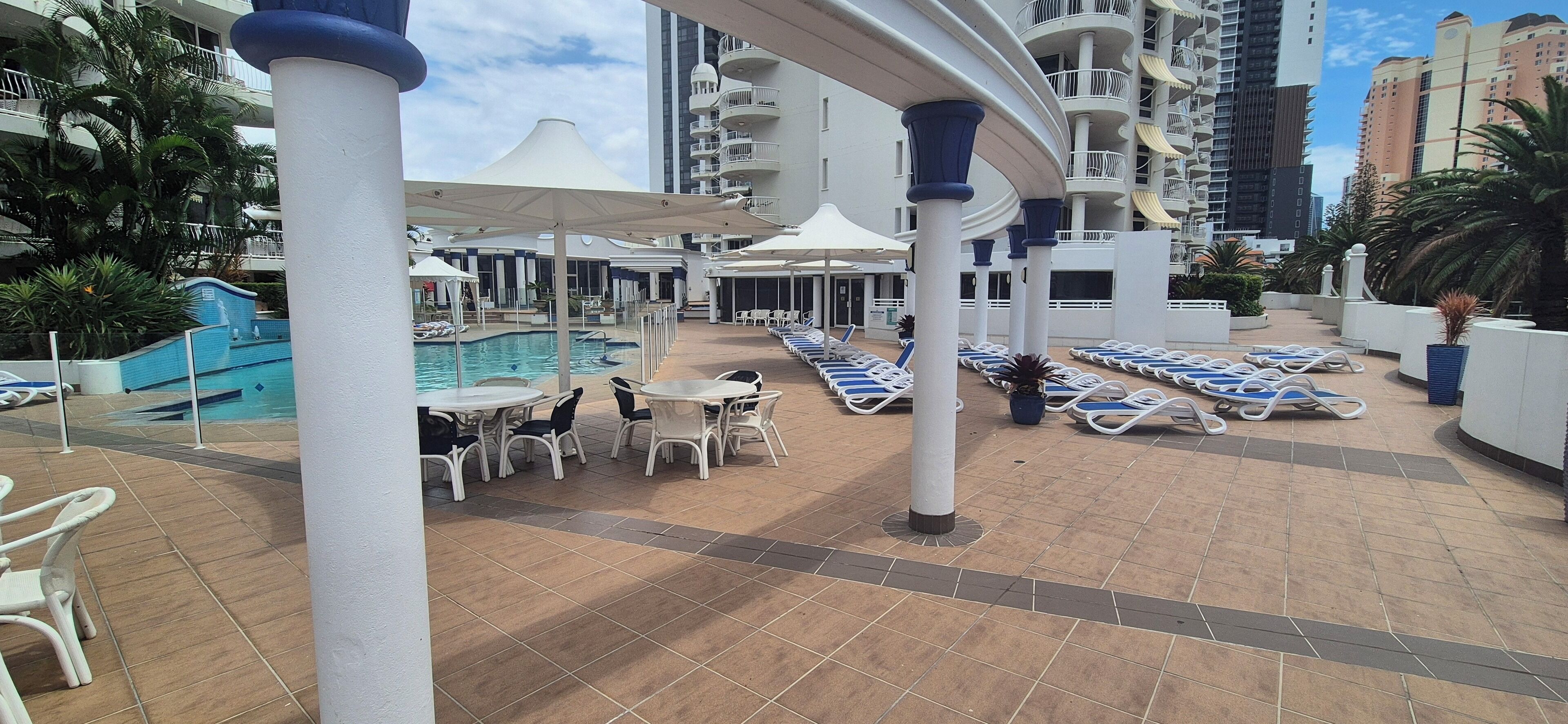 Uma  área de piscina no terraço com espreguiçadeiras, guarda-sóis e piscina.