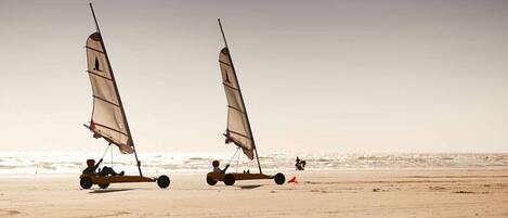 Two sailboats on a sandy beach with the ocean in the background.