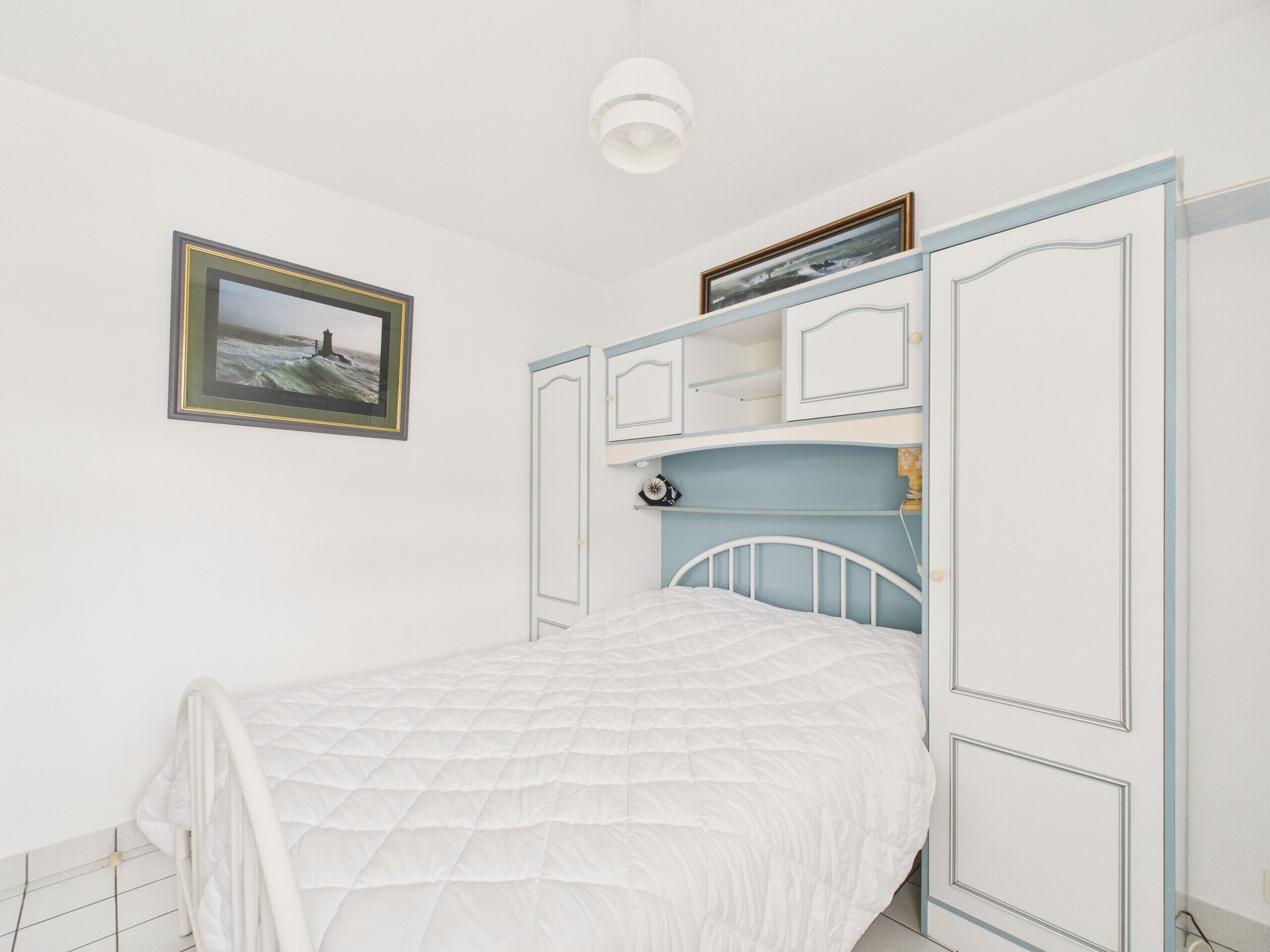 Une chambre à coucher avec un lit, un tableau encadré au mur et des étagères intégrées.