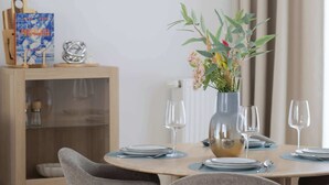 A dining area with a round table, grey upholstered chairs, a vase with flowers, and a painting on the wall. - Stylish Apartment | Balcony, Air Conditioning, Workspace (Warszawa)