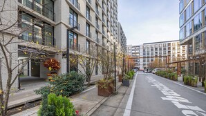 A modern urban street with a bike lane, buildings with balconies, and seasonal foliage. - Stylish Apartment | Balcony, Air Conditioning, Workspace (Warszawa)