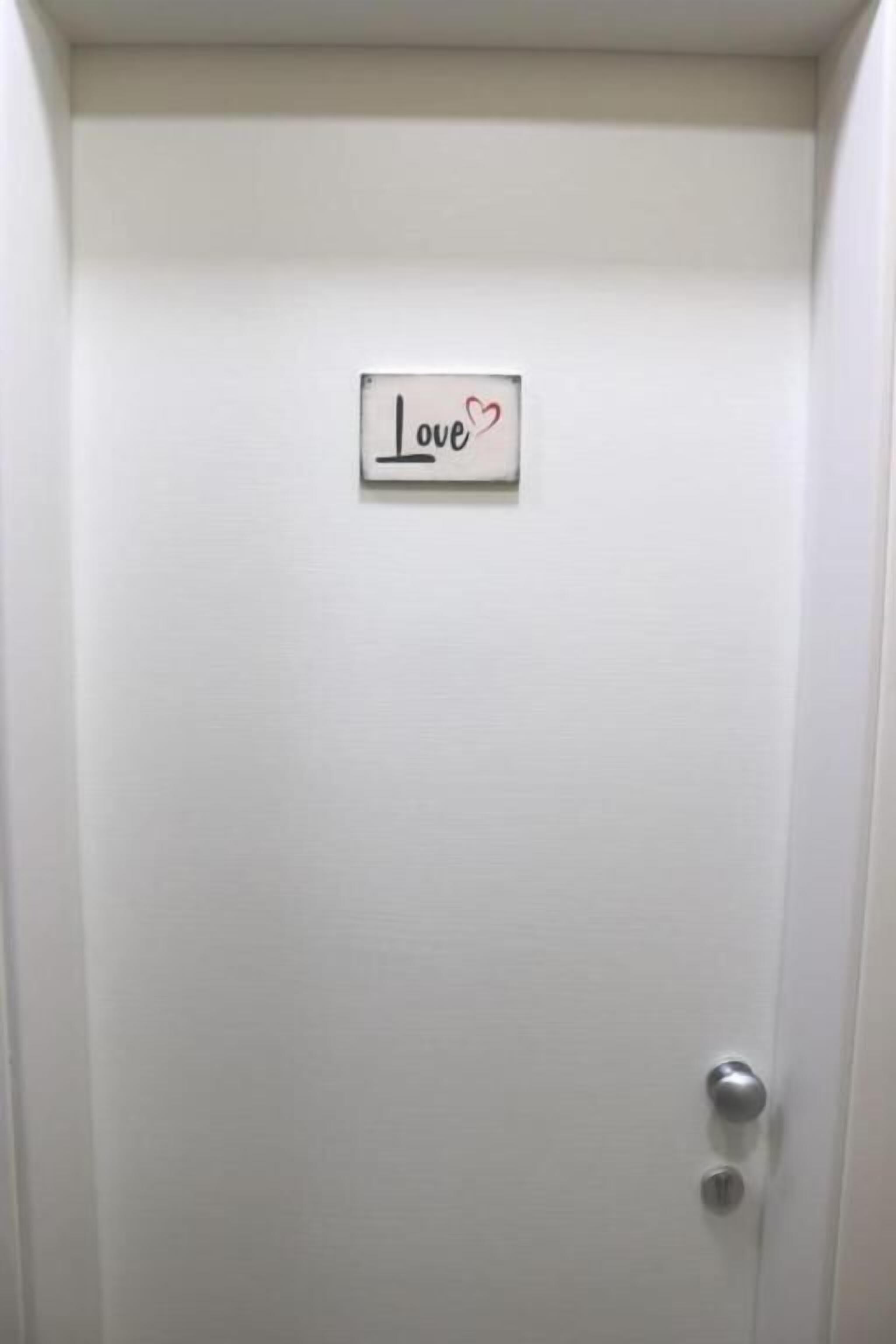 A white door with a sign that reads "Love" and a heart symbol.