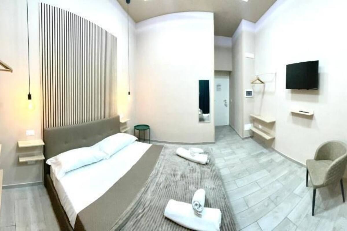 Une chambre d’hôtel moderne dotée d’un grand lit, d’une télévision, d’un coin salon et d’une salle de bain.
