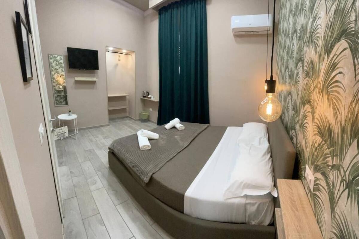 Une chambre d’hôtel moderne dotée d’un lit à la forme arrondie, d’un téléviseur à écran plat, d’une petite table, d’un miroir et d’un espace douche.