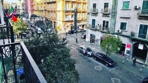 Μια φωτογραφία δρόμου με κτίρια, αυτοκίνητα και πεζούς.
