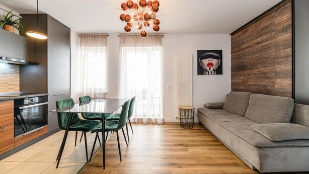 A modern living room with a dining area, a sofa, and a chandelier.