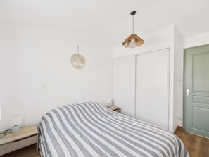 Ein Schlafzimmer mit Bett, Nachttisch, Lampe und einer Tür.