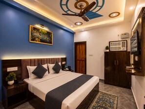 Een hotelkamer met een bed, een plafondventilator, een schilderij, een kledingkast en een televisie.