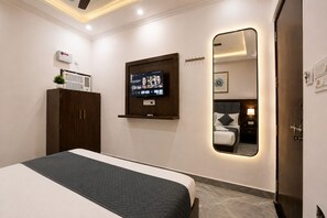 Une chambre d’hôtel moderne équipée d’un lit, d’un téléviseur fixé au mur, d’un miroir et d’une armoire.