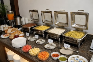 A buffet with various food items and serving utensils. - Hotel Dwarkadhish Plaza (Ayodhya)