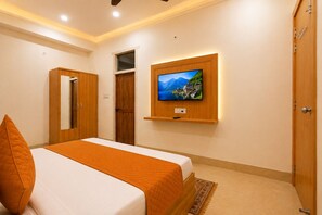 Een slaapkamer met een bed, een aan de muur bevestigde televisie en een kledingkast.