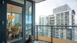 A modern apartment with a balcony, a dining area with a table and chairs, and a Buddha statue. - King Bed | Mins to Stampede | Cgy Twr View | UG Pk (Calgary)