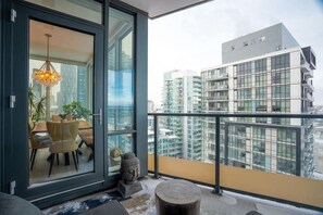 A modern apartment with a balcony, a dining area with a table and chairs, and a Buddha statue. - King Bed | Mins to Stampede | Cgy Twr View | UG Pk (Calgary)