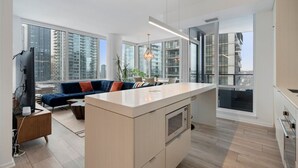 A modern apartment with a kitchen, living area, and large windows offering city views. - King Bed | Mins to Stampede | Cgy Twr View | UG Pk (Calgary)