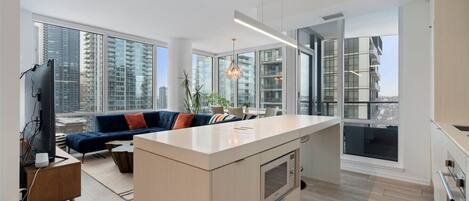 A modern apartment with a kitchen, living area, and large windows offering city views.