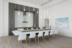 A modern kitchen with a central island, white chairs, pendant lighting, and a large painting on the wall. - King Bed | Mins to Stampede | Cgy Twr View | UG Pk (Calgary)