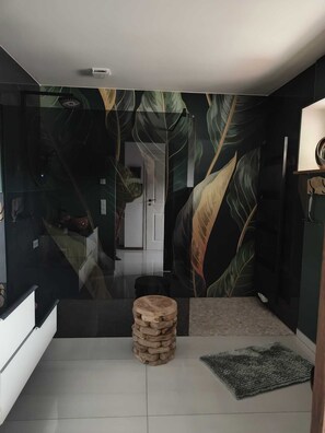 Ett rum med modern design, inrett med en stor spegel, en träpall och en vägg med ett mönster.