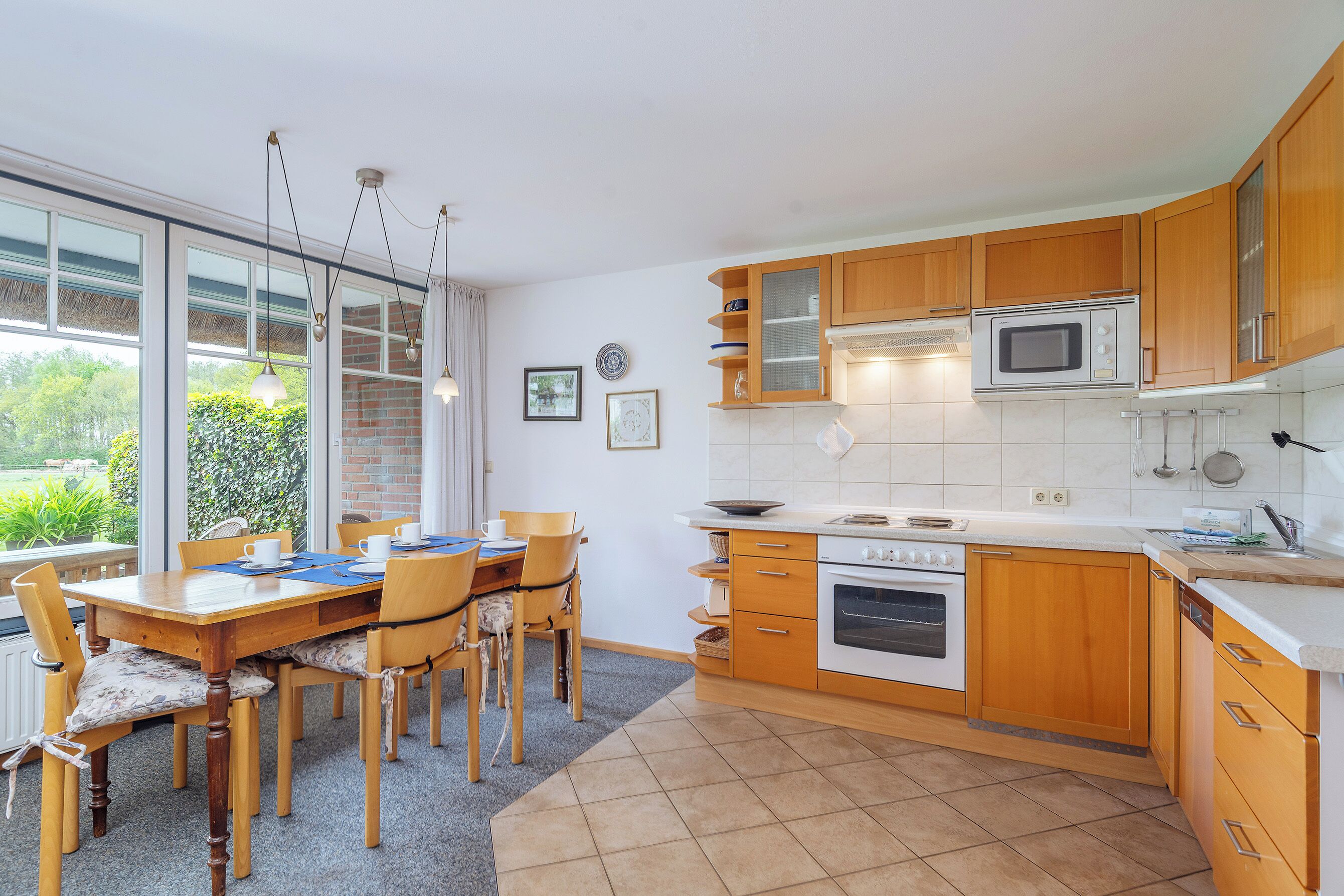 A kitchen with wooden cabinets, a microwave, an oven, and a dining area with chairs and a table.