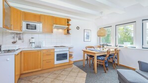Eine moderne Küche mit Holzschränken, einer Mikrowelle, einem Backofen und einem Essbereich mit Tisch und Stühlen.