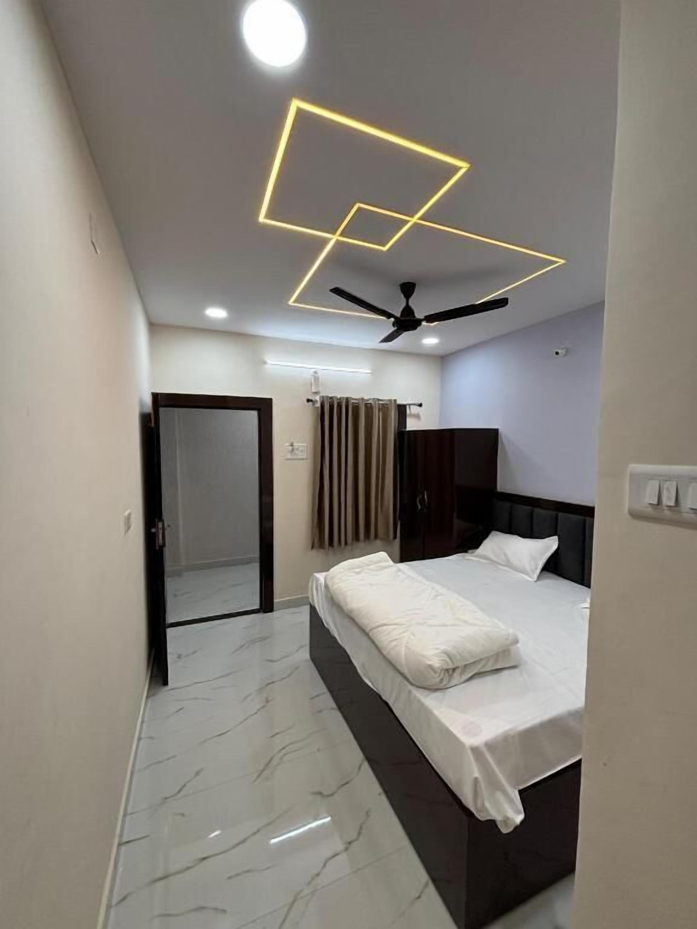 A modern bedroom with a bed, ceiling fan, and geometric light fixture.