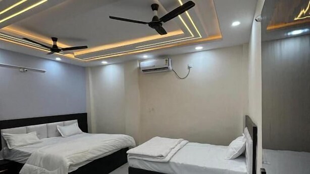 Une chambre d’hôtel moderne dotée de deux lits, d’un ventilateur de plafond, d’un éclairage encastré et d’un sol en marbre.