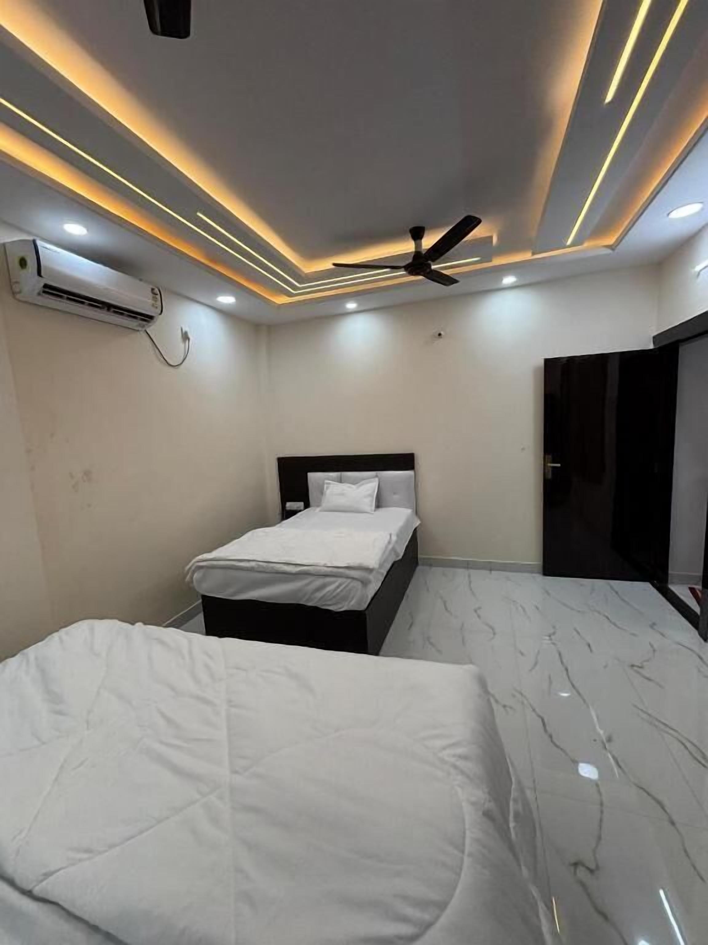 A modern bedroom with a bed, a ceiling fan, recessed lighting, and an air conditioning unit.