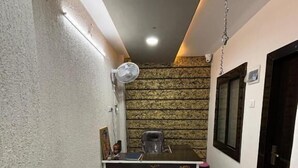 Un couloir étroit avec un comptoir d’accueil, un ventilateur de plafond et un papier peint à motifs.