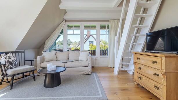 Quarto moderno no estilo loft, com uma janela ampla, sofá, mesa de centro e televisão.