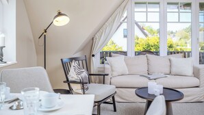 Um quarto acolhedor com um sofá, uma cadeira, uma mesa e um abajur.