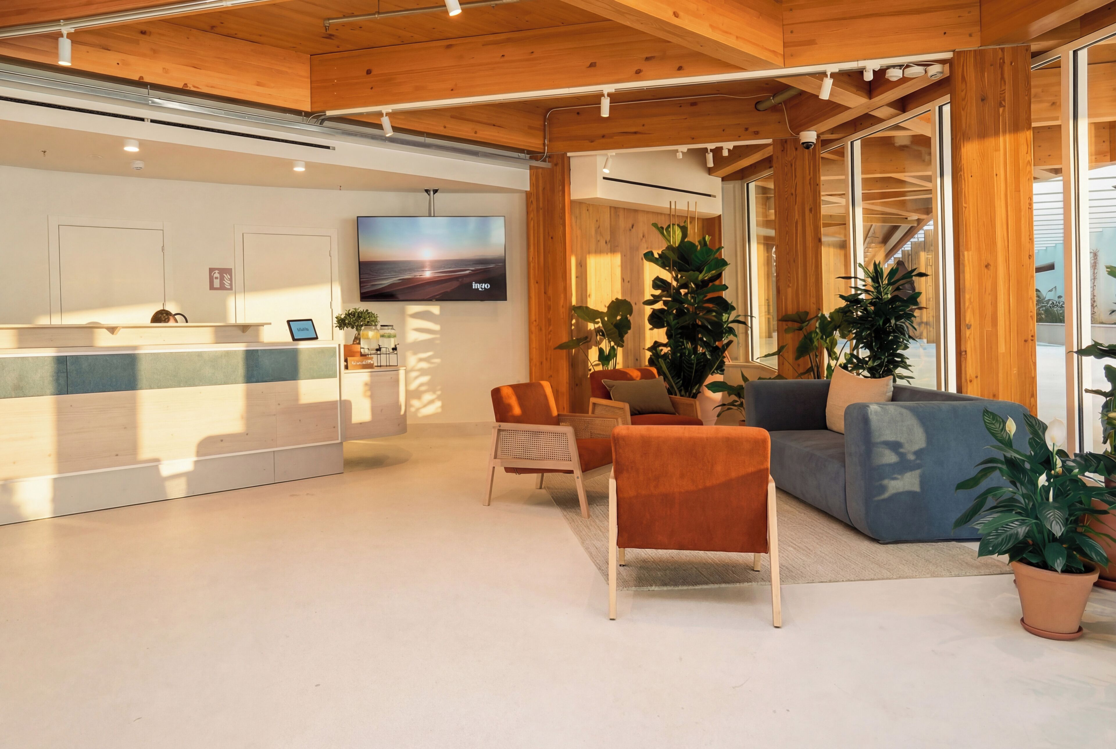 A modern interior with a reception desk, seating area, and large windows.