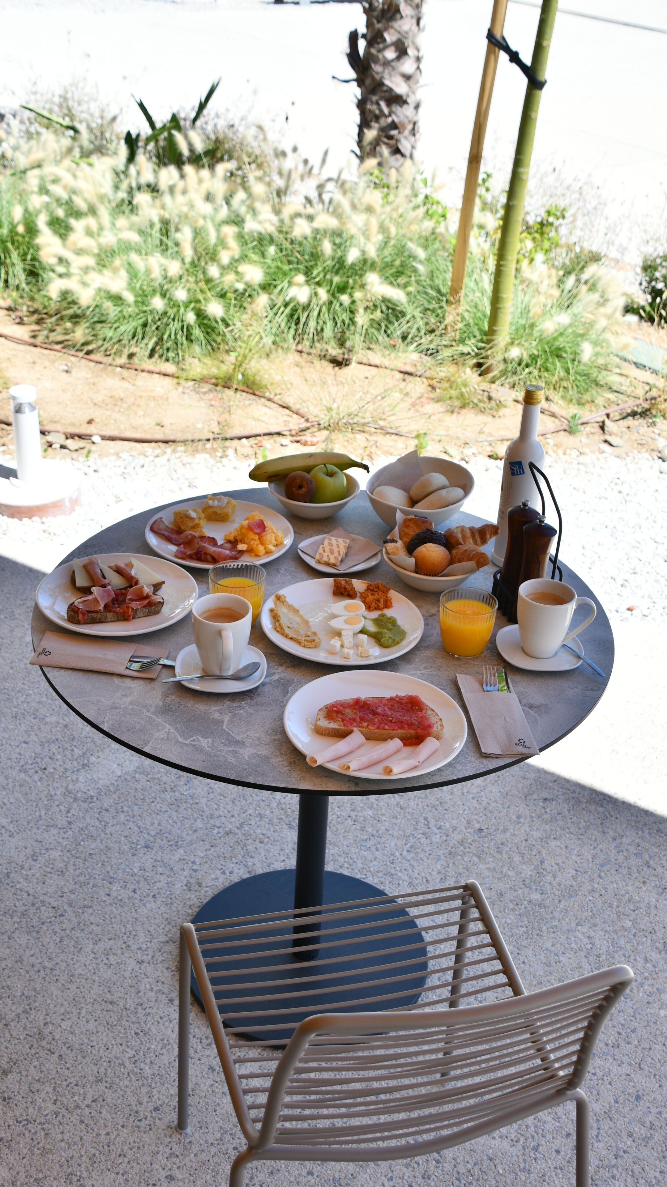 A round table with breakfast items, a chair, and a table lamp.