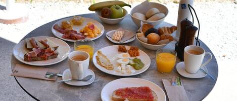 A round table with breakfast items, a chair, and a table lamp.