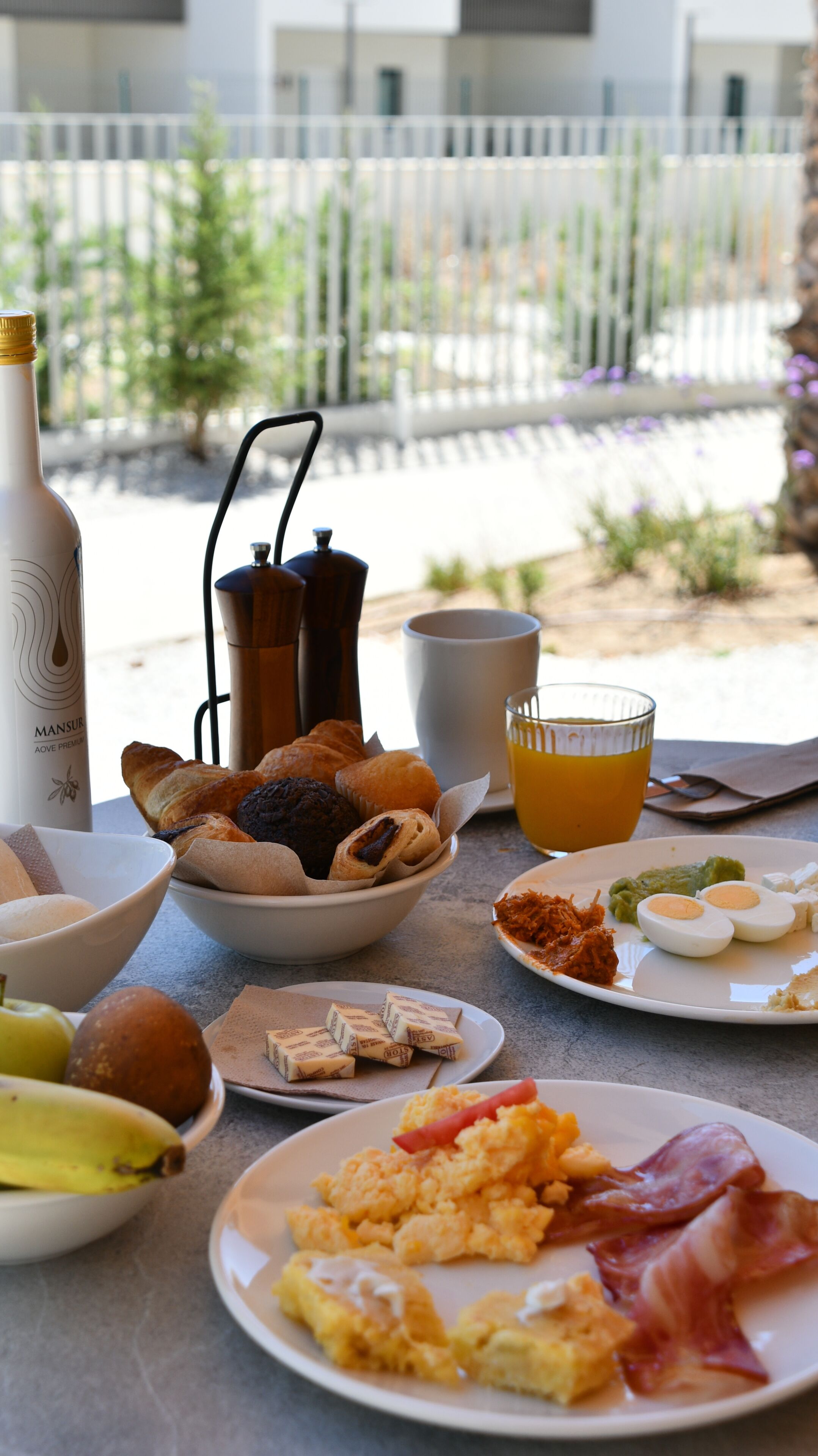 A breakfast table with various food items, a coffee pot, and a bottle.