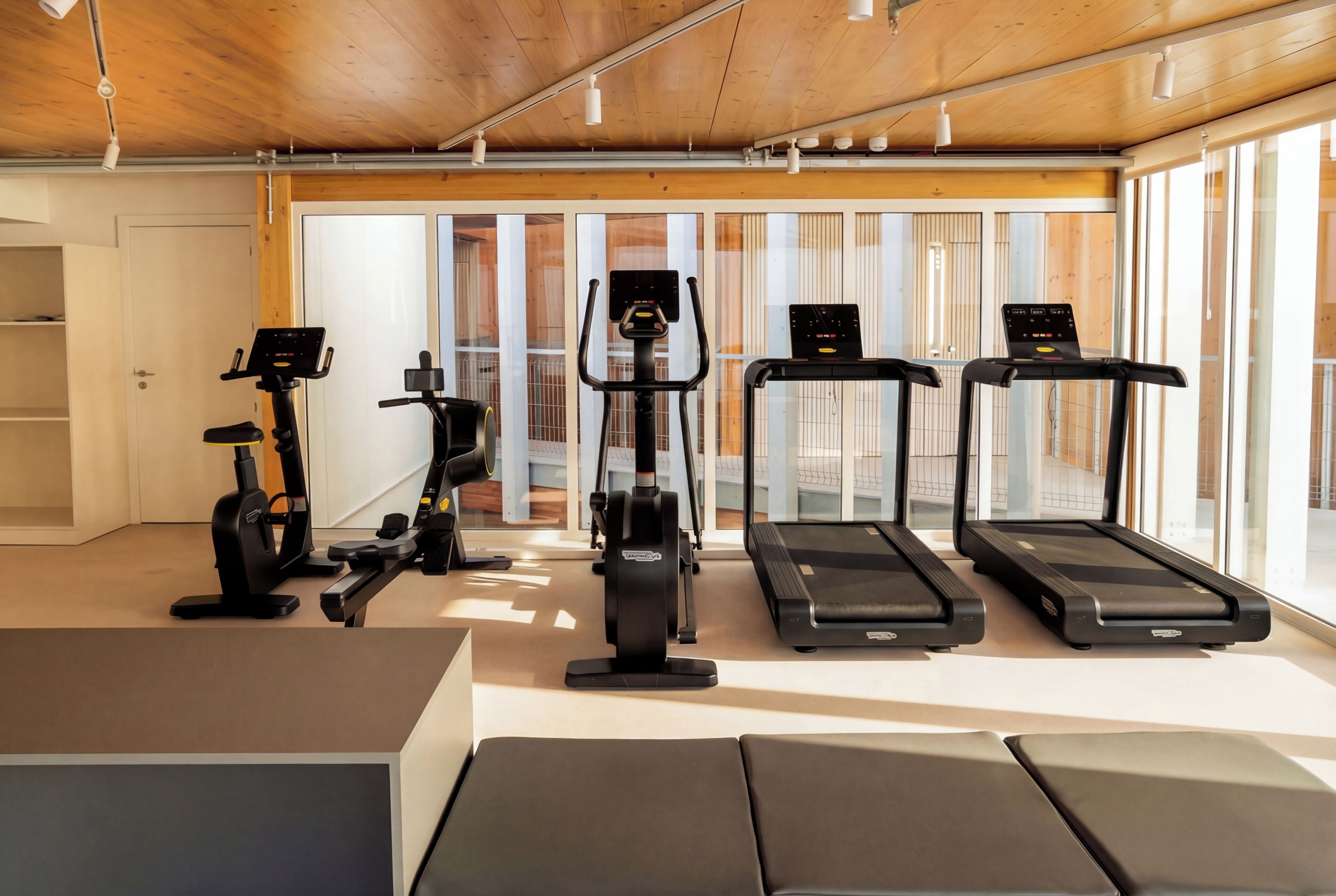 Un gimnasio con cintas de correr, elípticas y una bicicleta estática.
