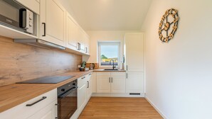 A modern kitchen with white cabinets, a wooden countertop, and a Bosch oven. - Vacation home "Huus Klee" in Kating for up to 4 people (Kating)
