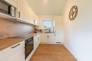 Eine moderne Küche mit weißen Schränken, einer Holz Arbeitsplatte und einem Bosch-Ofen.
