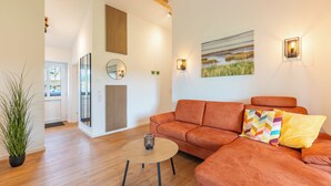 A modern living room with a sofa, a round coffee table, and a potted plant. - Vacation home "Huus Klee" in Kating for up to 4 people (Kating)