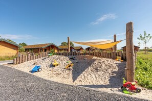Ein Kinderspielbereich mit Sand, Spielzeug und einem Holenzaun.