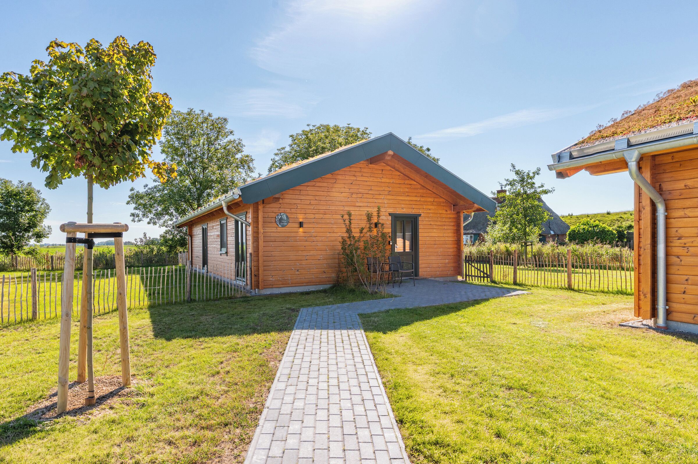 Une cabane en bois avec une allée pavée, un petit jardin et un ciel dégagé.