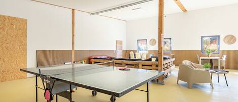 A ping pong table with wheels, a wooden bench, and a wall with vertical wooden slats.
